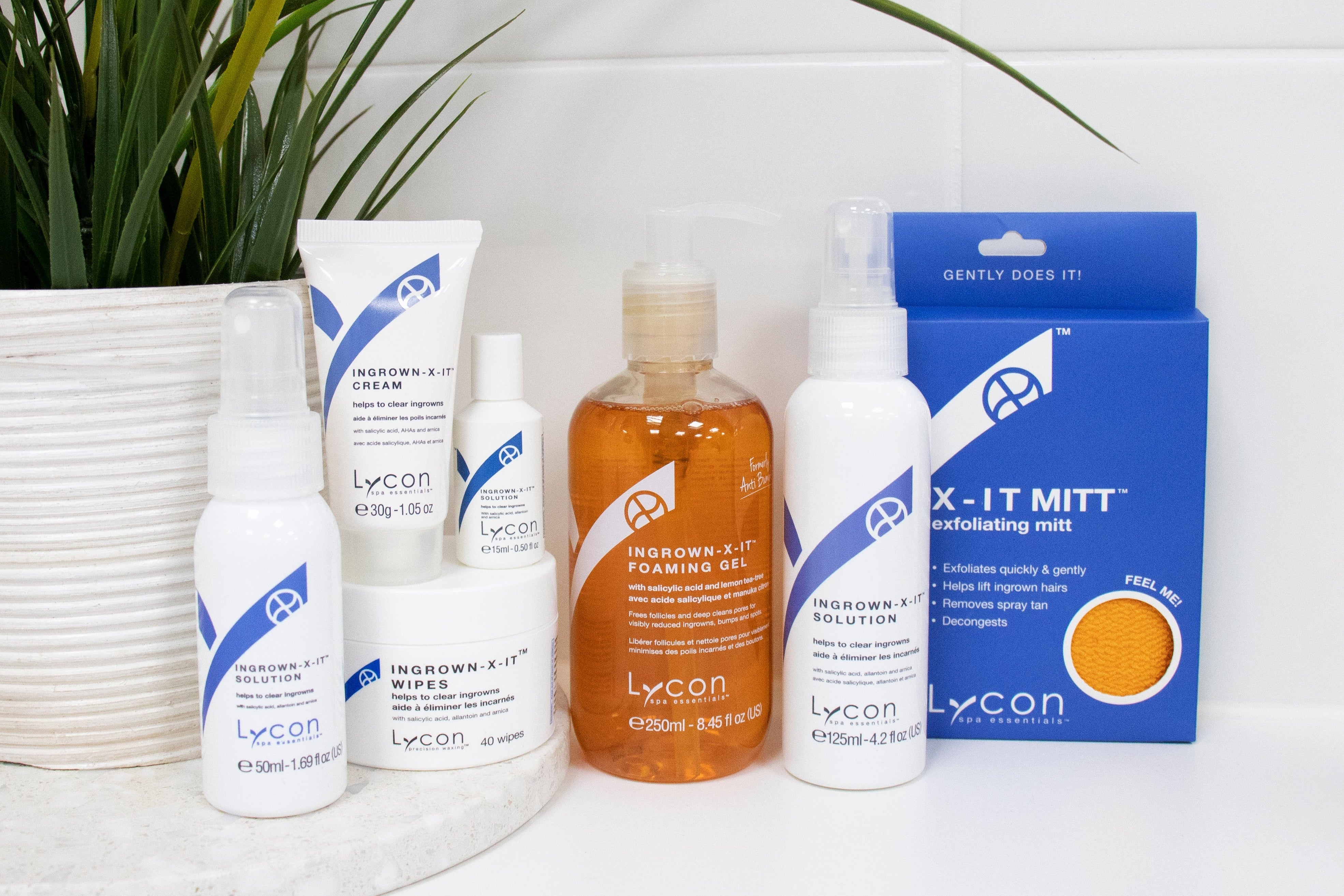 Collection of ingrown-x-it products on a white surface with a plant in the background