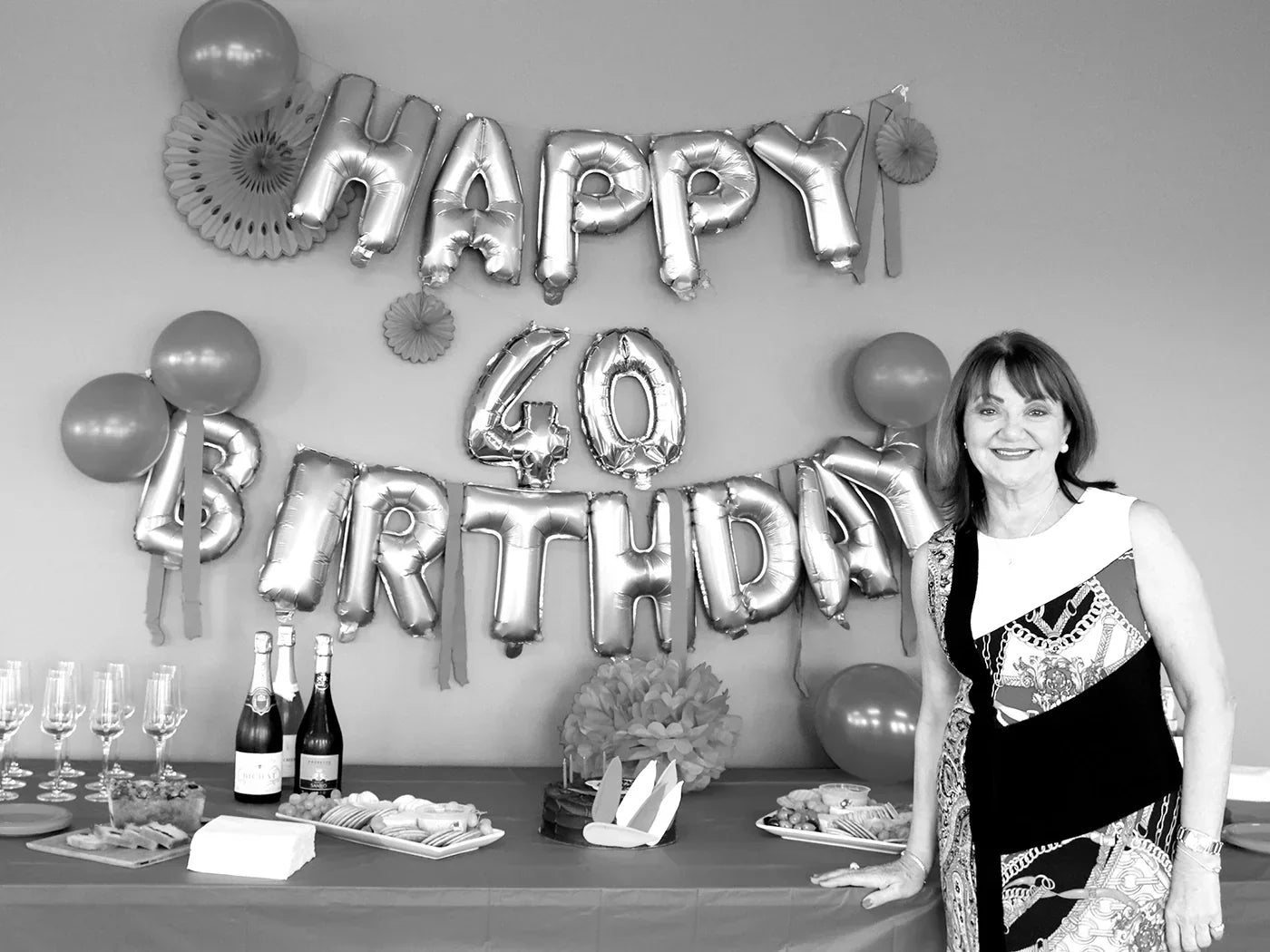 CEO of LYCON Cosmetics, Lydia Jordane smiling in front of balloons that read "happy 40th birthday"