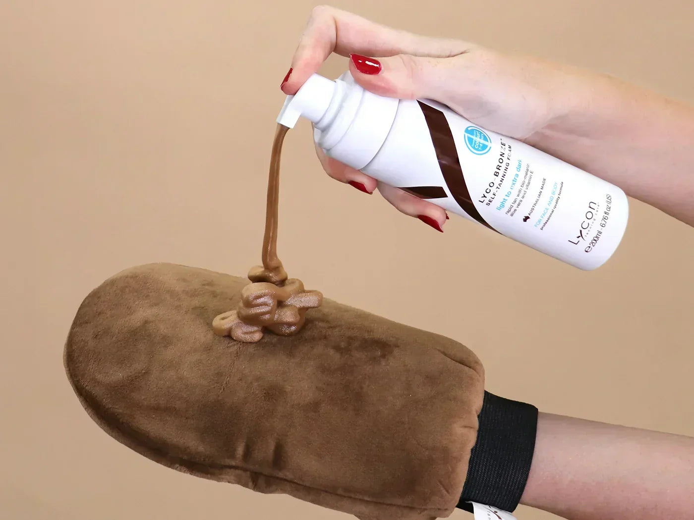 A photo of LYCO-BRONZE Self-Tanning Foam being pumped onto LYCO-BRONZE Application Mitt