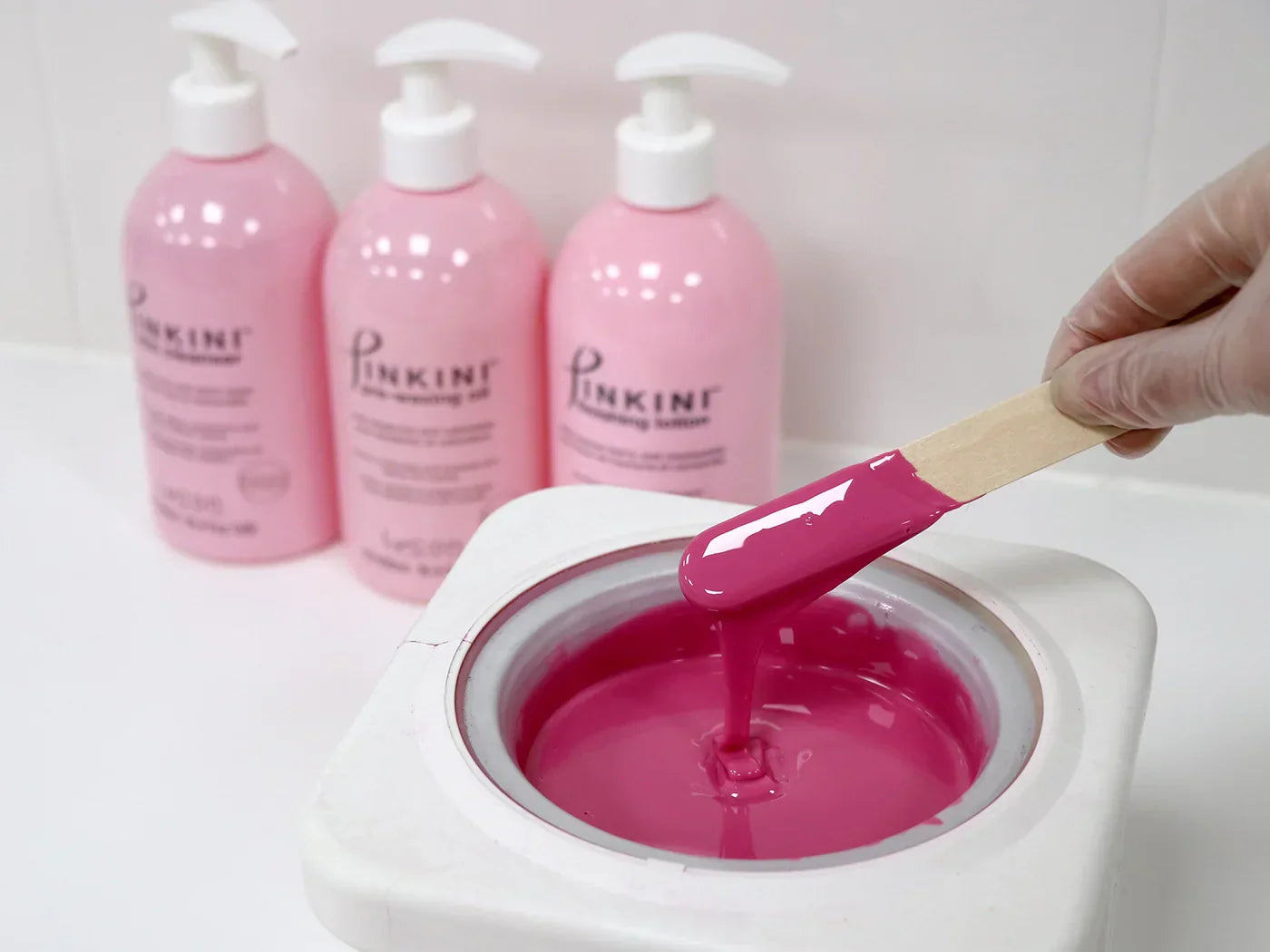 PINKINI hot wax melted in pot in from of PINKINI lotion bottles