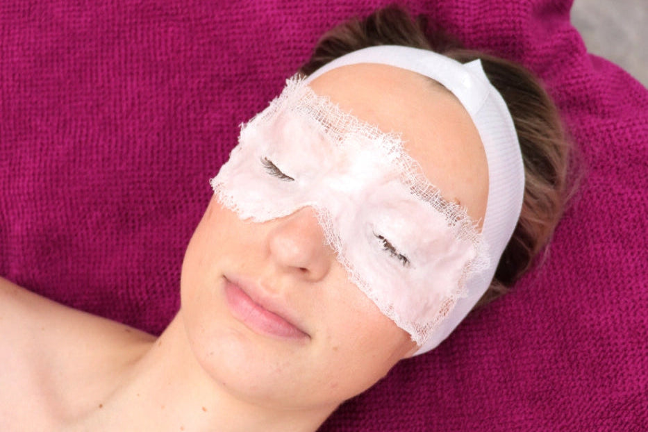 A woman laying peacefully on a salon bed receiving the Thermo Active - Eye Discover Treatment using the LYCON Skin Thermo Active Paraffin Mask